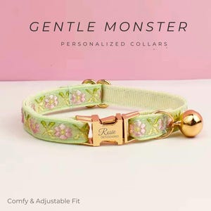 Könnte beinhalten: Hellgrünes personalisiertes Halsband für Haustiere mit floralem Muster und goldfarbenen Beschlägen. Der Kragen hat eine Schnalle mit dem eingravierten Namen "Rosie" und eine kleine Glocke. Der Text "GENTLE MONSTER PERSONALIZED COLLARS" ist oben zu sehen.