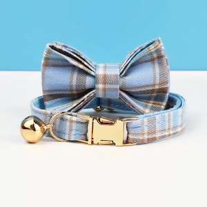 Peut inclure: Un ensemble collier et nœud papillon pour animaux de compagnie à carreaux bleus. Le collier est doté d'une boucle en métal doré et d'une petite cloche. Le nœud papillon est attaché au collier.