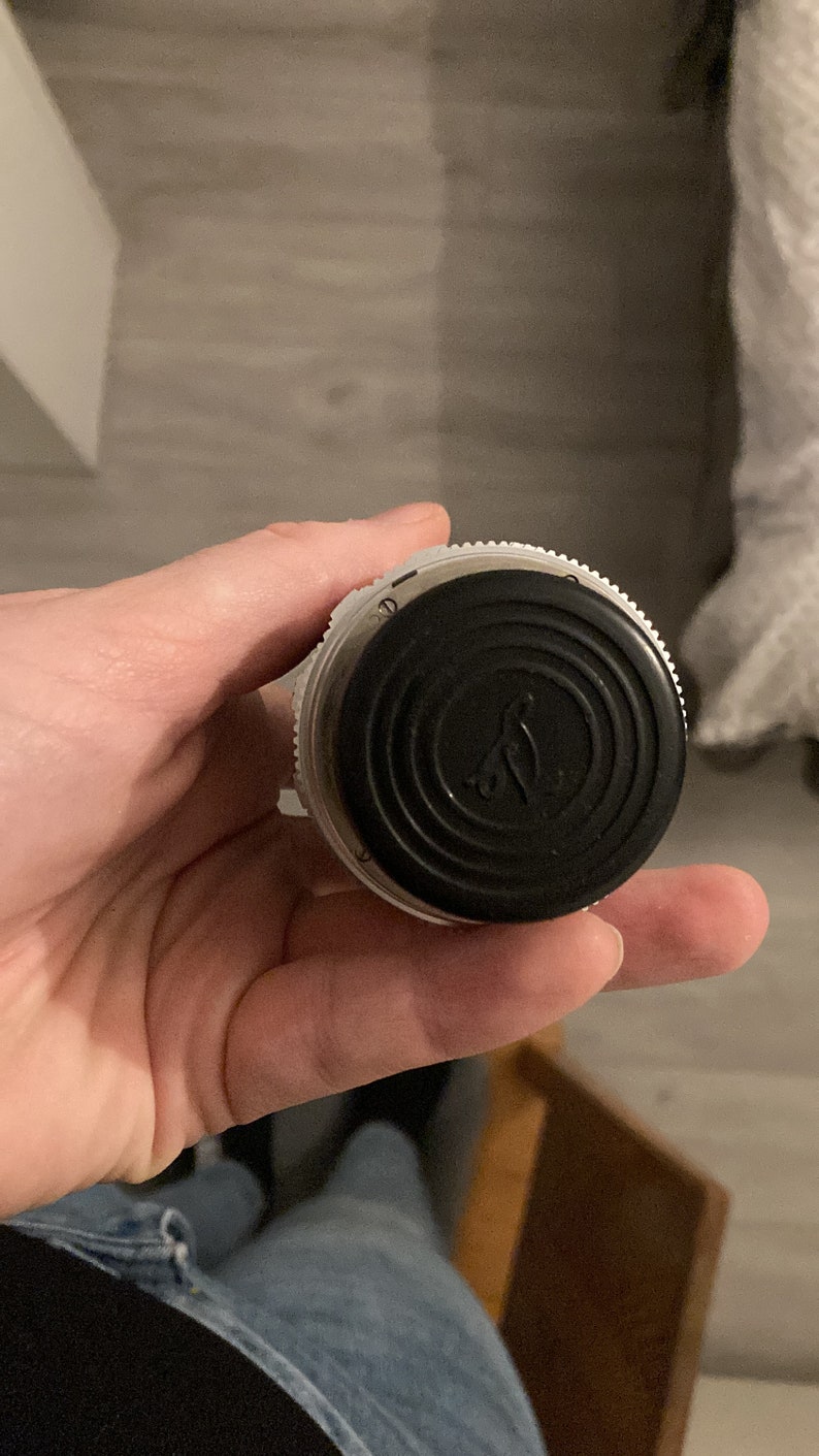May include: A black and white bottle stopper with a circular design and a small bird logo. The stopper is made of plastic and has a textured surface.