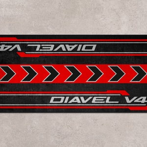Op de afbeelding: Zwart en rood grafisch ontwerp met de tekst "Diavel V4" die twee keer wordt herhaald. Het ontwerp bevat vijf rode pijlen die naar rechts wijzen.