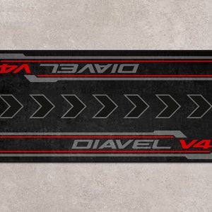 Op de afbeelding: Zwarte en rode motorfiets vloermat met de tekst "Diavel V4" en vijf pijlen die naar rechts wijzen.