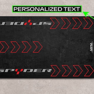 Op de afbeelding: Een zwarte muismat met het woord "SPIDER" in wit en rood, en drie rode pijlen aan elke kant. De tekst "PERSONALIZED TEXT" staat bovenaan en onderaan de muismat.