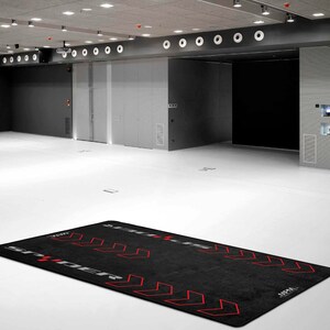 Op de afbeelding: Zwarte trainingsmat met rode pijlen en de tekst "STREET" en "APPA" erop gedrukt.