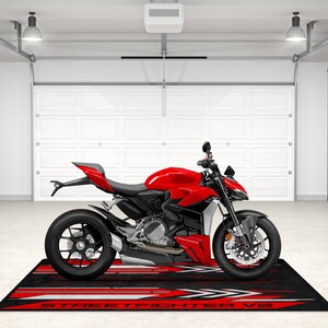 Puede incluir: Una motocicleta roja con ruedas negras y una alfombra de suelo con estampado negro y rojo con el texto "STREETFIGHTER V2".