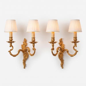 Par de apliques de pared antiguos de bronce dorado estilo Luis XV, con diseño de volutas rococó de dos brazos, copas en forma de tulipán y motivos de hojas.