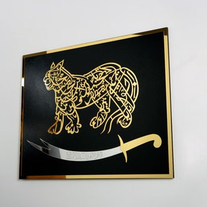 Puede incluir: Un fondo negro con un contorno dorado presenta una imagen estilizada de un le&oacute;n hecha de caligraf&iacute;a &aacute;rabe. Una espada plateada con mango dorado se coloca debajo del le&oacute;n.
