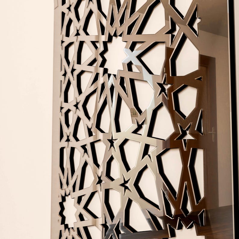 May include: A silver metal panel featuring a geometric star and line design. The panel's repeating pattern of stars and angular shapes creates a modern and intricate appearance. It is likely used for interior design or architectural purposes.