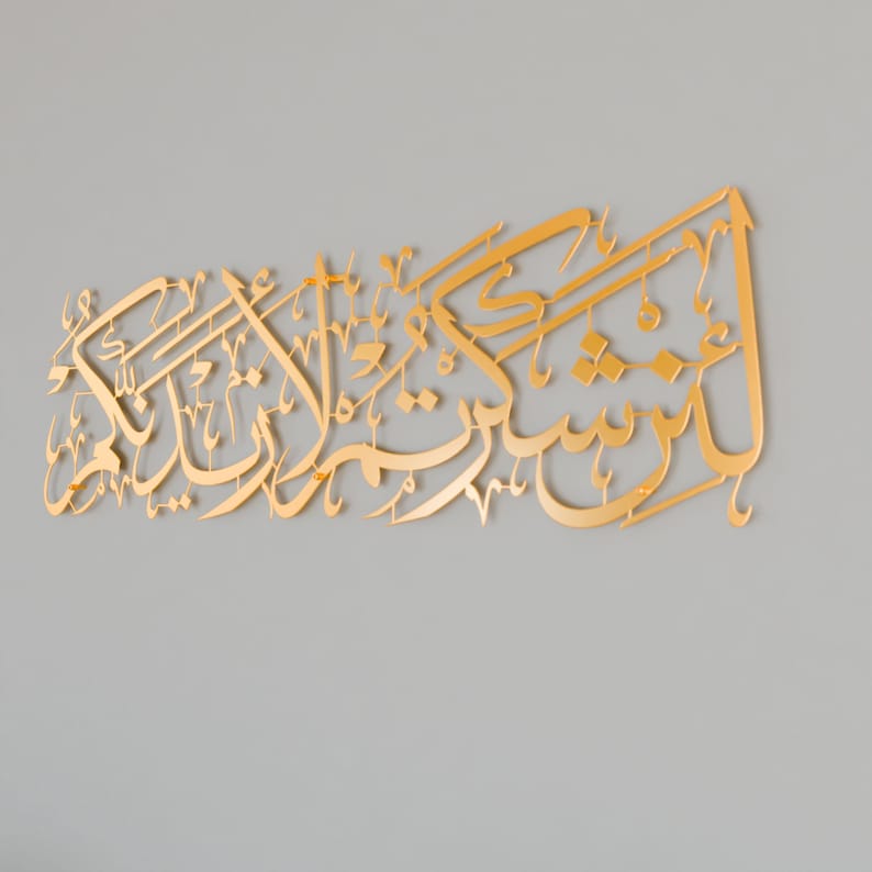 May include: Gold Arabic calligraphy wall art with intricate lettering. The text reads "Subhana-alladhi sakh-khara-lana hadha wa ma kunna lahu muqrinin wa inna ila Rabbi-na la munqalibun".