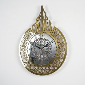 May include: A gold-colored wall clock with an intricate geometric design and the Arabic word "Allah" in a decorative font. The clock face is silver with black hands and Roman numeral markings.