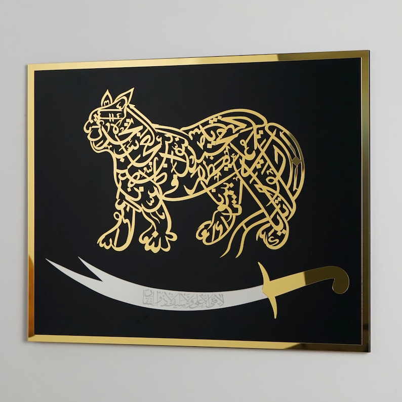 Puede incluir: Una pieza de arte de pared enmarcada en negro con un dise&ntilde;o met&aacute;lico dorado de un le&oacute;n con caligraf&iacute;a &aacute;rabe. El le&oacute;n est&aacute; de pie sobre una espada con un mango dorado.