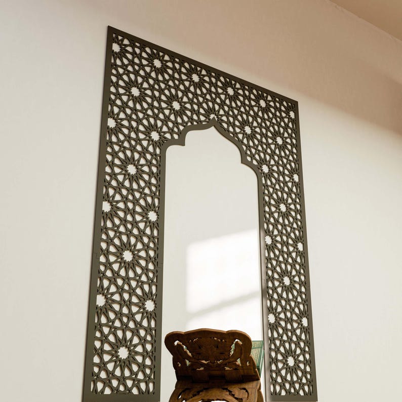 May include: A decorative wall mirror with a dark brown geometric pattern frame. The frame has an arched top and intricate star and floral designs. The mirror is rectangular with a clear reflection.