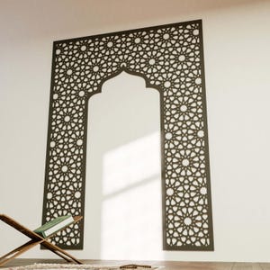 May include: A dark brown, intricately patterned wall panel in an arch shape. The panel features a repeating star and geometric design. A wooden book stand with a book and prayer beads are in the foreground, suggesting a religious theme.