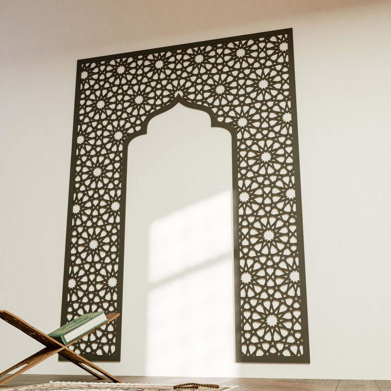 May include: A dark brown, intricately patterned wall panel in an arch shape. The panel features a repeating star and geometric design. A wooden book stand with a book and prayer beads are in the foreground, suggesting a religious theme.