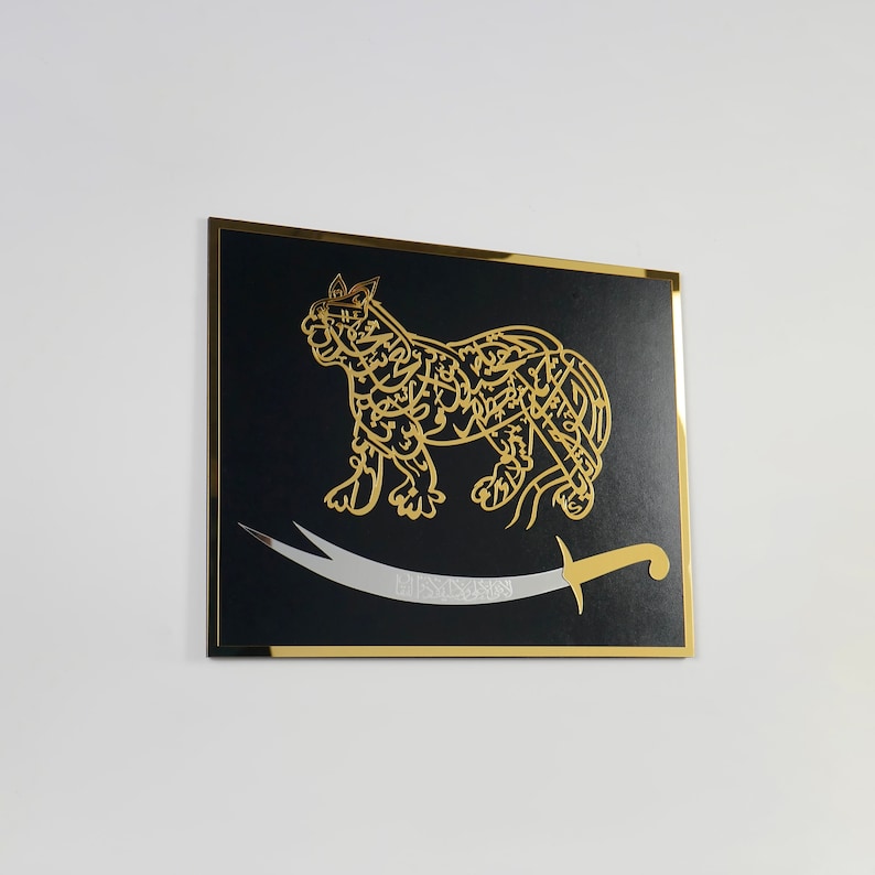 Puede incluir: Una pieza de arte de pared enmarcada en negro con un dise&ntilde;o caligr&aacute;fico dorado de un le&oacute;n y una espada plateada. El le&oacute;n est&aacute; mirando hacia la derecha y la espada est&aacute; curvada.