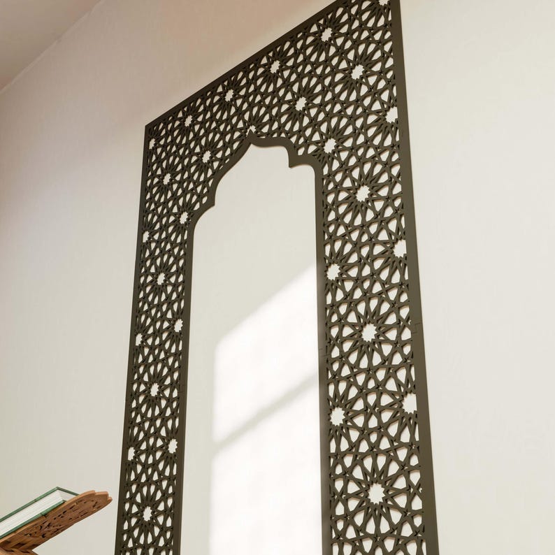 May include: A dark brown, intricately patterned wall panel in an arch shape. The panel features a repeating geometric design with star-like shapes. The panel is mounted on a white wall, creating a striking contrast. The design is reminiscent of Islamic art.