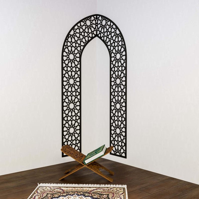 May include: A wooden prayer stand with a green book resting on it, in front of a black and white geometric arch wall decal.