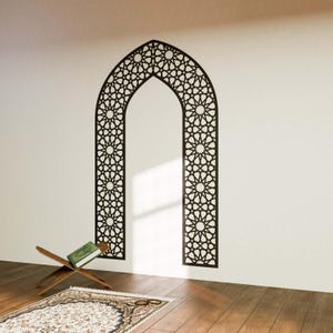 May include: A black and white geometric archway wall decal with an intricate star pattern. The decal is applied to a white wall with a wooden floor and a prayer rug in the foreground.