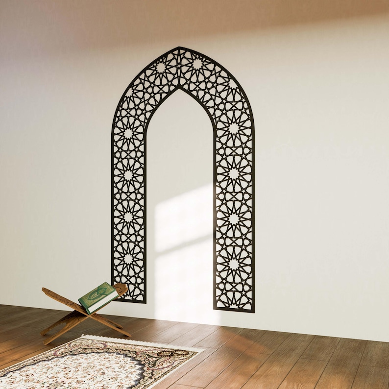 May include: A black and white geometric archway wall decal with an intricate star pattern. The decal is applied to a white wall with a wooden floor and a prayer rug in the foreground.