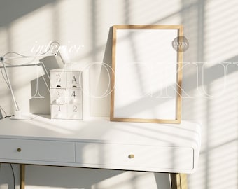 Può includere: Una cornice in legno con interno bianco è appoggiata su una scrivania bianca. Una lampada da scrivania bianca e un piccolo calendario bianco sono anche sulla scrivania. L'immagine ha il testo "interior MOCKUP".