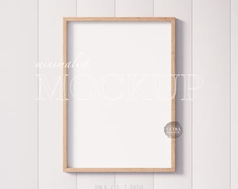 May include: A minimalist mockup of a wood framed picture on a white wood panel wall. The frame is empty and ready for your design.