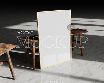 May include: A gold-framed mockup poster with a white background, standing on a white marble floor. Two rustic wooden stools are in the foreground, with one on the left and one on the right of the poster. The text "interior MOCKUP" is superimposed on the poster.