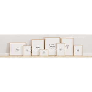 May include: A set of eight wood framed picture frames in various sizes, all with white mats and a white background. The frames are arranged in a row on a light wood surface. The text "Your design here" is written in black on each frame.