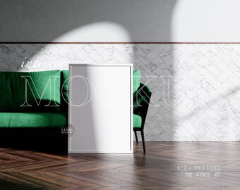 Può includere: Un mockup di cornice bianca in un soggiorno con un divano e una sedia verdi. La parete dietro la cornice è piastrellata con marmo bianco.