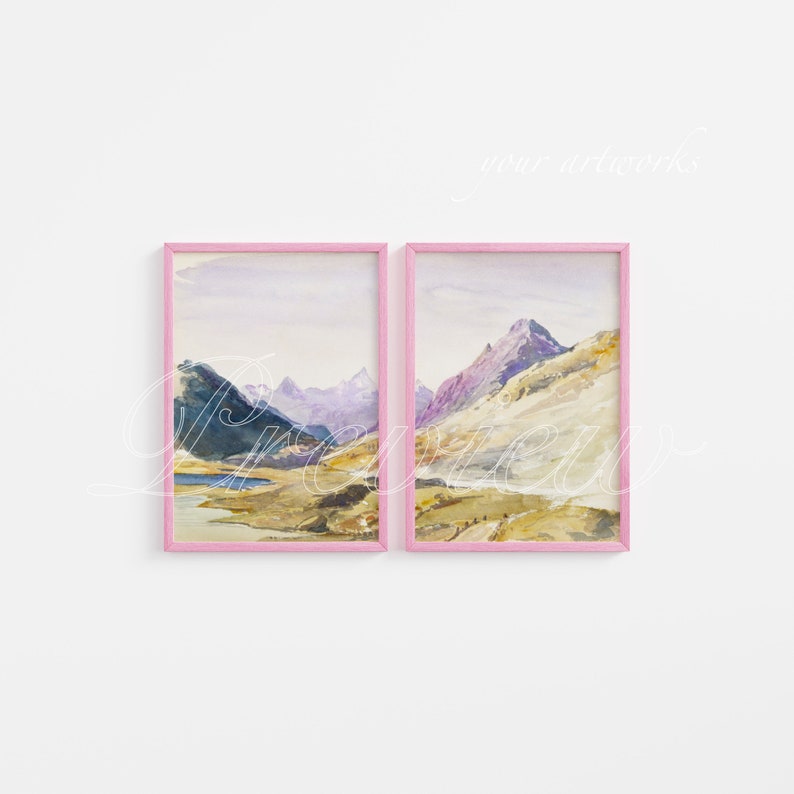 May include: Two framed watercolor paintings of mountain landscapes. The paintings are in pink frames and are hung on a white wall.