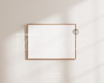 May include: A rectangular wooden picture frame with a white interior, hanging on a light beige wall. The word "minimalist" is written at the top, and the word "MOCKUP" is written in large, transparent letters across the frame. The frame is a 7 x 5 DIN A series.