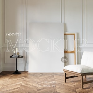 Puede incluir: Una maqueta de lienzo blanco apoyada en una pared blanca con una silla de madera y una mesa pequeña con velas y un libro. El texto "canvas MOCKUP" está escrito en blanco sobre el lienzo.