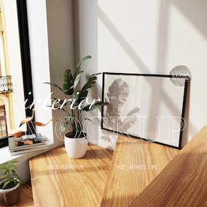 May include: A black picture frame mockup with a white background, sitting on a wooden table with a potted plant and a decorative bird sculpture. The text "interior mockup" is written in white on the table.