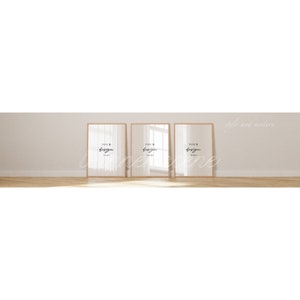 May include: Three empty picture frames with a light wood frame and a white mat. The frames are hanging on a light beige wall. The text "YOUR DESIGN HERE" is visible in each frame.