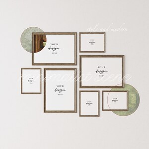 May include: A wall gallery featuring seven brown wood framed pictures with white mats. The frames are arranged in a staggered pattern. The frames are empty and have the text "YOUR DESIGN HERE" written in black cursive. The wall is white and there are two green and white circular shapes behind the frames.
