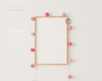 Könnte beinhalten: Ein Holzrahmen-Mockup mit weißem Hintergrund, umgeben von einer Schnur mit rosa Wollkugeln. Der Text "interior mockup" ist in Weiß an der Wand geschrieben.