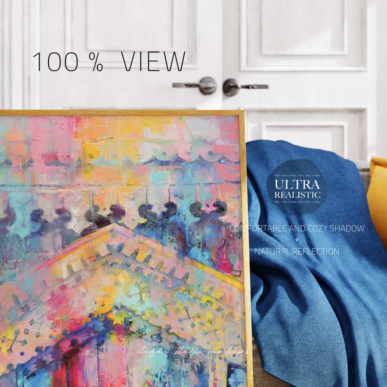 May include: A framed abstract painting with a colourful, textured design. The painting features a mix of pink, blue, yellow, and green hues. The frame is gold and the painting is leaning against a blue blanket.