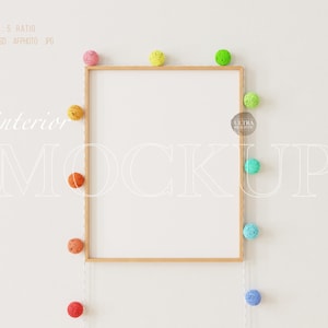 Puede incluir: Una maqueta de marco de madera con fondo blanco. El marco está rodeado de una cadena de luces de bolas de algodón de colores. El texto "interior mockup" está escrito en blanco en la pared.