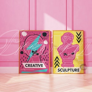 May include: Two framed prints with a pink background. The print on the left features a stylized line drawing of a woman's face with a lightning bolt and the word "CREATIVE". The print on the right features a stylized line drawing of a bust sculpture with the word "SCULPTURE".