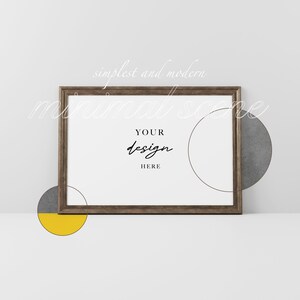 May include: A brown wooden frame with a white background and the text "YOUR design HERE" inside. The frame is on a white surface with two gray and yellow circles.