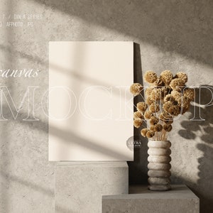 Puede incluir: Una maqueta de lienzo blanco con un fondo beige. El lienzo está sobre un pedestal de hormigón. Un jarrón con flores secas está sobre un pedestal de hormigón delante del lienzo.