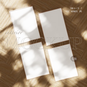 May include: Four blank picture frames with wooden frames are arranged in a square on a wooden floor. The frames are all the same size and are arranged in a grid pattern. The floor is made of light brown wood planks.