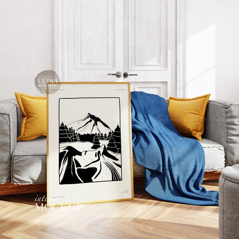 May include: A black and white illustration of a mountain range with trees in a gold frame. The frame is on a wooden floor in front of a grey sofa with yellow cushions and a blue throw.
