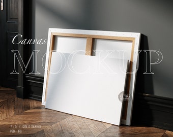 Könnte beinhalten: Ein weißer Leinwand-Mockup mit einem Holzrahmen, der an einer dunkelgrauen Wand lehnt. Die Leinwand ist leer und bereit für Ihr Design. Der Text "Canvas Mockup" ist in Weiß auf schwarzem Hintergrund geschrieben.