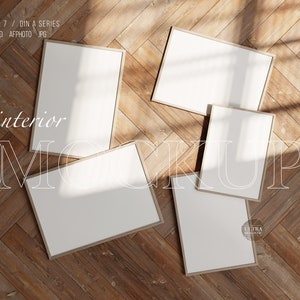 Può includere: Cinque cornici per foto vuote di diverse dimensioni sono disposte su un pavimento in legno. Le cornici sono in legno e hanno una finitura marrone chiaro. Il pavimento è in assi di legno e ha un colore marrone chiaro. Le cornici sono disposte a spina di pesce. Le cornici sono tutte vuote e pronte per essere riempite con foto.