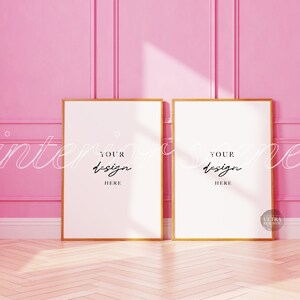 May include: Two gold framed posters with white backgrounds against a pink wall. The text "YOUR DESIGN HERE" is written on each poster.