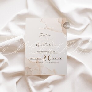 May include: A wedding invitation with a watercolor background in shades of beige and brown. The invitation reads "Together with their families, John and Natalie request the honor of your presence at their wedding, October 20, 20XX, at six o'clock in the evening."