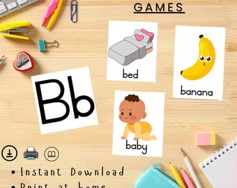 May include: A wooden surface displays phonics matching games with illustrations of a bed, banana, and baby. The letter "Bb" is featured, along with the words "Instant Download", "Print at home", and "Easy to use". Various stationery items are scattered around.