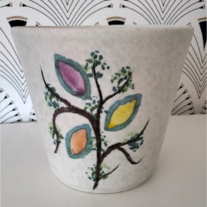 Op de afbeelding: Witte keramische plantenpot met een gestileerd boomontwerp met groene, paarse, gele en oranje bladeren.