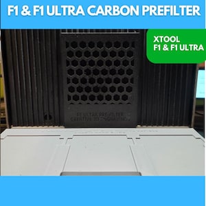 May include: A black carbon prefilter with a honeycomb pattern, labeled "F1 & F1 ULTRA CARBON PREFILTER." The image also displays the text "XTOOL F1 & F1 ULTRA" and "F1 ULTRA PRE-FILTER CREATIVE 3D ENGRAVING."