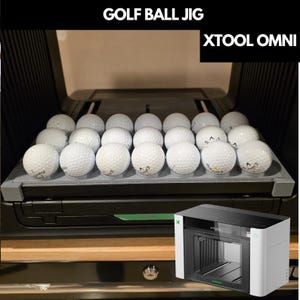 以下が含まれることがあります： xTool Omniレーザーマシン内に配置された、21個の白いゴルフボールをグリッド状に保持するグレーのプラスチック製ゴルフボールジグ。上部には「GOLF BALL JIG」および「XTOOL OMNI」の文字があり、隅にはマシンの小さな画像が表示されています。