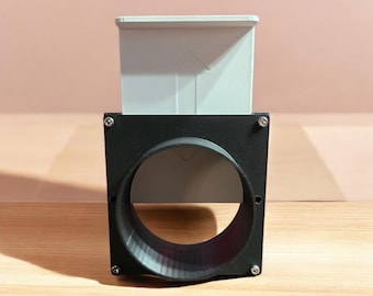 May include: A black and gray 3D printed adapter for a ventilation system. The adapter has a round opening and a square frame. The text "WORKS WITH ALL OUR ADAPTERS" is printed below the adapter.